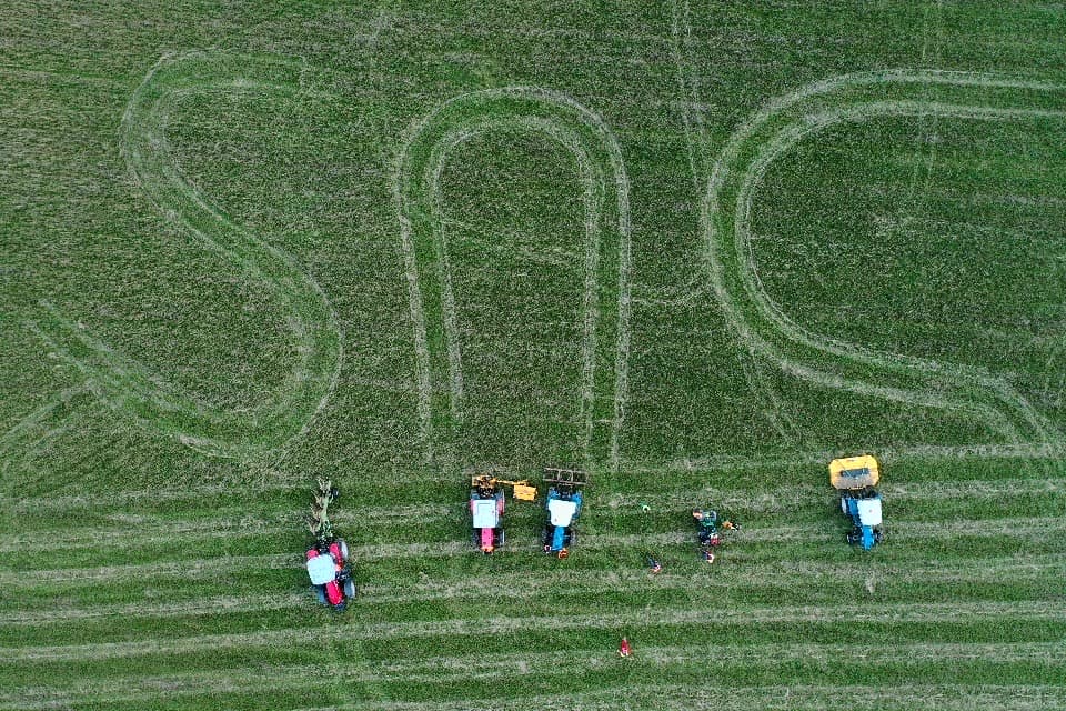 Drone photo of agriculture students who have cut the letters SNC into crops.