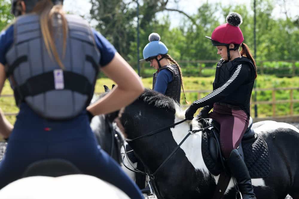A group of equine learners on horses being give instructions