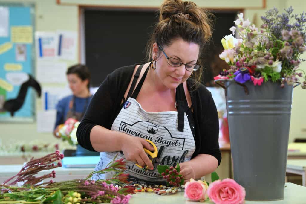 Adult learner in floristry workshop cutting flower stems.