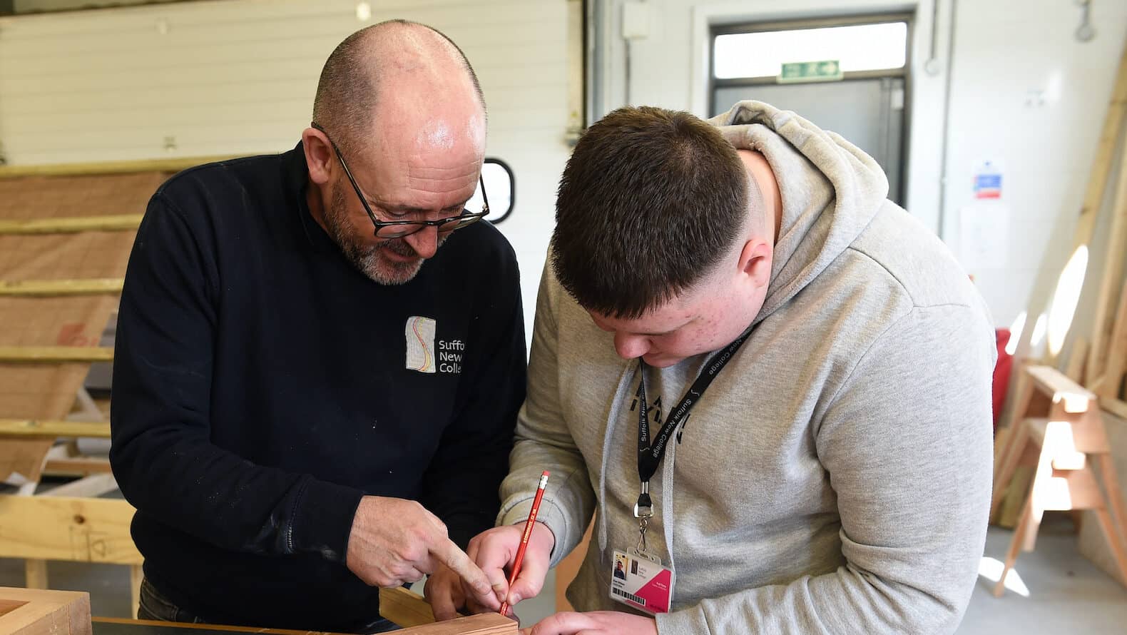 Learner and tutor marking out cuts on a block of wood