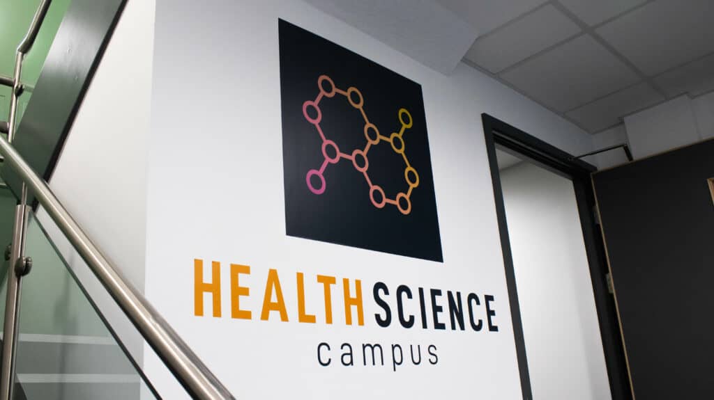 Health Science Campus logo displayed on a wall beside a staircase in the campus building.